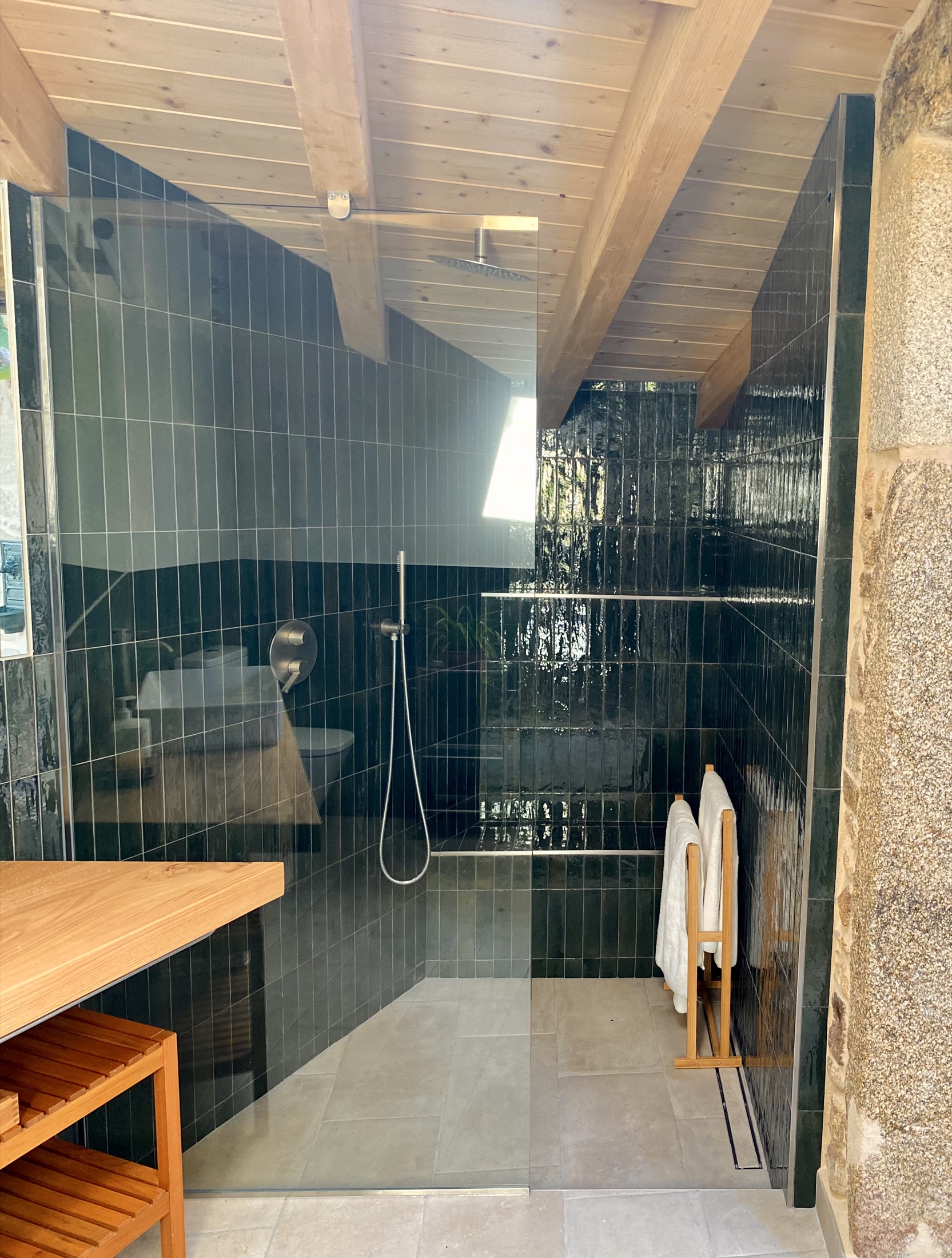 Baño reformado con madera y azulejo oscuro en Camboño